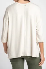 Remera color arena con efecto melange, de corte oversize, cuello redondo y mangas 3/4.