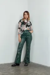 Pantalón de cuero sintético verde con corte recto, tiro alto y botones metálicos a lo largo de la pierna.