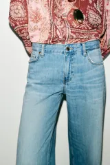 Jeans de tiro bajo color azul claro, con cinco bolsillos y pernera ancha. Cierre frontal con cremallera y botón.