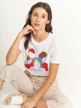 Remera blanca de corte oversized con estampado de figuras femeninas abstractas en colores rojo, marrón, celeste y lila.