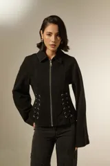 Sobrecamisa de jean color negro con cierre frontal, cuello clásico y detalle de cordones laterales ajustables con ojalillos metálicos.