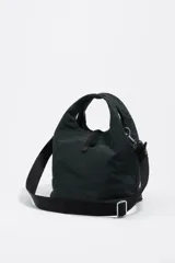 Bolso bandolera de estructura blanda marca Bimba y Lola, confeccionado en nylon con detalles en cuero. Presenta doble asa de mano, correa de tejido regulable y extraíble, cierre de cordón y logo metálico en el frente.