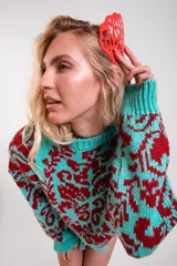Sweater de punto con diseño estampado en color turquesa y bordó, de corte holgado, con cuello redondo y mangas largas.