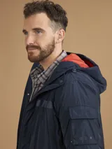 Campera de abrigo azul marino con capucha, cierre frontal con botones y cremallera, múltiples bolsillos y forro interior naranja.