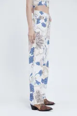 Pantalón de tiro alto y piernas amplias, confeccionado en gabardina de algodón estampada con diseño floral en tonos azul, beige y marrón.