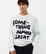 Suéter de tejido jacquard color blanco con estampa frontal de letras negras 'Something Almost Great', de cuello redondo y manga larga con calce boxy.