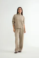 Conjunto de dos piezas compuesto por un sweater de cuello alto con aberturas laterales y un pantalón de corte recto y tiro alto, confeccionado en tejido de punto suave.