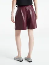 Bermuda gris de cuero sintético con pinzas, bolsillos laterales y cinturón con hebilla metálica.