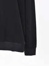 Buzo de cuello redondo, manga larga, con puños y ruedo acanalados, confeccionado en tejido liso de color gris oscuro.