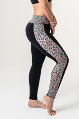 Calza deportiva de tiro alto con cintura elástica reforzada. Presenta un diseño bicolor que combina paneles laterales y faja con estampado animal print en tonos coral y turquesa sobre una base negra.