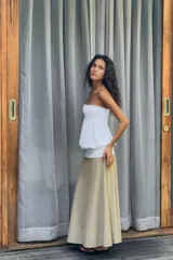 Vestido midi de diseño strapless con escote recto. Presenta un cuerpo superior blanco con textura fruncida y una falda inferior en tono beige con caída fluida.