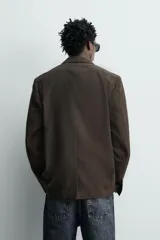 Blazer cruzada regular fit confeccionada en tejido con mezcla de lana y algodón, en color marrón. Cuenta con solapas de pico, manga larga, bolsillos con solapa en la cadera y cierre frontal de botonadura doble.