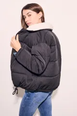 Campera puffer negra con cuello de corderito color crema, cierre frontal con cremallera y cordón ajustable en el ruedo.