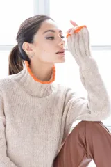 Sweater de punto color beige con cuello alto y ribete naranja en cuello y puños.