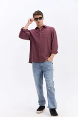 Camisa rústica de manga larga color gris oscuro, con cuello clásico, cierre frontal con botones y un bolsillo aplicado en el pecho.