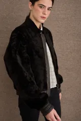 Campera tipo bomber de textura afelpada en color negro, con cierre frontal, cuello alto y puños y ruedo elásticos en cuero.