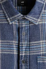 Camisa de sarga de algodón con diseño a cuadros, cuello inglés, bolsillo superior y mangas largas con puños abotonados.