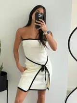 Minivestido strapless color crudo con ribete negro y lazo negro en la falda.