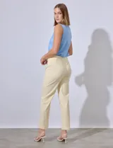 Pantalón de vestir color crema con finas rayas verticales en amarillo pálido. Tiene bolsillos simulados en la parte delantera y corte recto.