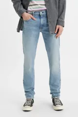 Jean de corte slim taper con tiro bajo, confeccionado en denim elástico de tono celeste claro con efecto desgastado.