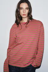 Camiseta de manga larga con cuello redondo y bajo recto, confeccionada en tejido de punto a rayas horizontales en tonos rosa fucsia y verde oliva.