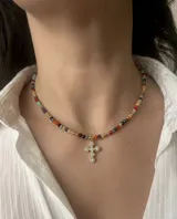 Gargantilla corta de cristalitos facetados multicolor, con cuentas doradas y dije colgante de cruz dorada con incrustaciones de circonias.