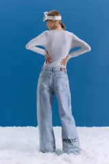 Jean de corte oversize y tiro medio-alto, en color celeste con lavado tipo ice y acabado con foil transparente. Presenta un diseño de pierna ancha y estampa en la parte trasera.