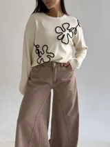 Sweater de punto color marrón chocolate con diseño floral bordado en cordón color crudo. Presenta cuello redondo, mangas largas y puños acanalados.