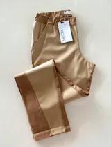 Pantalón combinado tostado, confeccionado con un panel frontal de cuerina elástica en tono camel y un panel posterior de gabardina con spandex en tono tostado. Presenta una cintura elastizada para mayor comodidad y costuras a la vista en contraste.