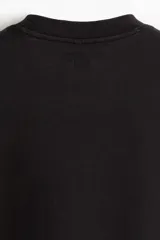 Remera deportiva negra de corte boxy, confeccionada en tejido funcional DryMove™ con efecto lavado. Tiene cuello redondo ribeteado acanalado y hombros caídos.