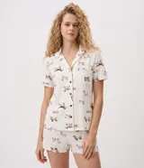 Pijama de viscolycra color beige con estampado de perritos marrones, compuesto por una camisa de manga corta con cuello solapa y botones frontales, y un short con cintura elástica.
