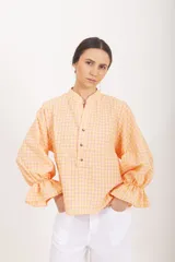 Blusa de manga larga abullonada con estampa cuadrillé en tonos rosado y amarillo, cuello mao y cierre frontal parcial con botones.