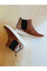 Botas cortas de cuero color marrón, estilo botineta con elásticos laterales negros, suela blanca de goma y detalle de arte pintado a mano en la parte trasera.