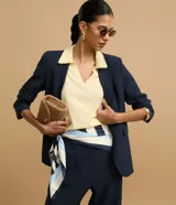 Blusa negra de punto con cuello polo, escote en V y mangas cortas. Detalle de mini perlas aplicadas en el cuello.