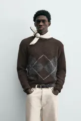 Jersey de punto marrón oscuro con diseño jacquard de rombos en gris y blanco, cuello redondo y manga larga.