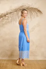 Conjunto de dos piezas compuesto por un crop top de breteles anchos y una pollera midi, ambos en color azul con detalles de bordado floral blanco en el ruedo y el lateral del top.