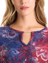 Blusa Ruby Rd. de corte holgado con diseño texturizado y estampado floral en tonos azul y bordó. Presenta cuello redondo con escote tipo keyhole y detalle metálico, mangas tres cuartos amplias y dobladillo asimétrico.