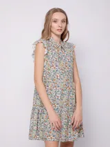 Vestido corto con estampado floral multicolor, cuello tipo camisa y cierre frontal con botones. Presenta volados en las sisas y un diseño de falda con volados en el ruedo.