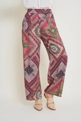Pantalón de seda estampado con motivos geométricos en tonos rojo, rosa, amarillo y negro. Tiene cintura elastizada y bolsillos laterales.