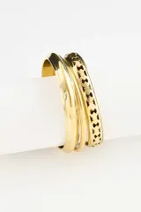 Set de pulseras rígidas de metal dorado, compuesto por tres piezas con diferentes texturas y diseños grabados.