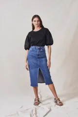 Remera negra de algodón con mangas cortas abullonadas que presentan detalles de encaje bordado y calado en los extremos.