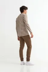 Conjunto de pijama compuesto por una remera de manga larga a rayas horizontales en tonos marrón y beige, y un pantalón tipo jogging color marrón con puños elásticos en los tobillos.