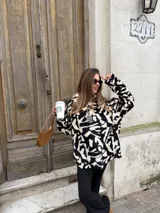 Buzo de peluche con estampado animal print en blanco y negro, de corte holgado, cuello alto y cierre frontal parcial con tirador metálico.