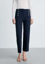 Pantalon de tiro medio con diseño recto y corte crop. Presenta detalles de botones decorativos efecto joya en la parte frontal y cierre oculto con cremallera y gancho.