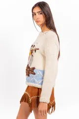 Sweater de punto color marfil, con cuello redondo, mangas largas y calce holgado. Presenta un bordado artesanal en el frente con diseño de dos músicos y un pez sobre fondo celeste.