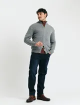 Cardigan de punto gris con cuello alto, cierre frontal de metal con doble cursor y bolsillos laterales. Presenta puños y cuello en tejido canalé.