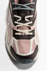 Calzado deportivo de diseño chunky, confeccionado en malla rosada con revestimientos en tonos marrón, beige y blanco. Cuenta con cierre de cordones, trabilla en la parte trasera y suela gruesa con relieve.