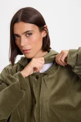 Campera de terciopelo color chocolate, con corte holgado, mangas murciélago y capucha desmontable. Presenta cierre frontal con botones a presión y bolsillos laterales.