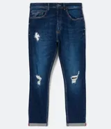 Pantalón de jean skinny azul oscuro con roturas en las rodillas y ruedo doblado.