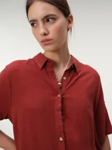 Camisa de manga corta color verde oliva, con cuello camisero, cierre frontal con botones y diseño fluido y relajado.